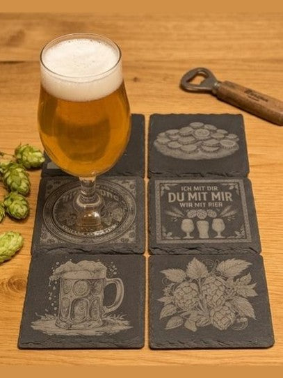 Seime-Kreativschuppen 6er-Set quadratische Schiefer-Untersetzer mit Bier-Gravuren auf einem Holztisch mit Bierglas